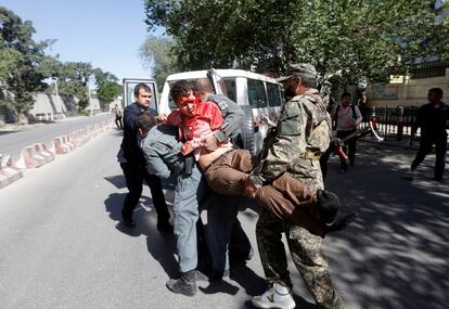 Miembros de las fuerzas de seguridad afganas cargan con un hombre herido cerca del lugar del atentado.