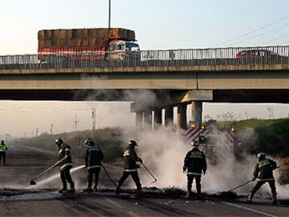 Los bomberos limpian las barricadas instaladas ayer por los trabajadores de los astilleros en Sevilla.