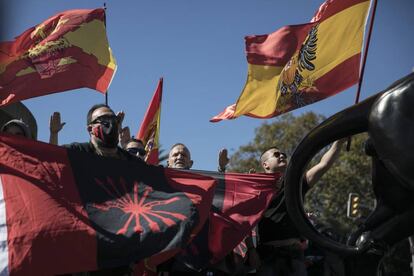 Ciudadanos con banderas preconstitucionales y con el símbolo de la falange, bajo la estatua de Colón en Barcelona, este lunes.