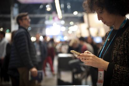 Una mujer consulta su teléfono móvil durante la primera jornada del MWC.