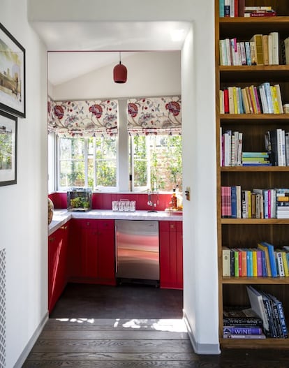 El bar, pintado en rojo, rompe con los tonos marrones del salón familiar. Ubicado en la trastienda de la biblioteca, está rematado por unas cortinas florales de Cowtan & Tout.