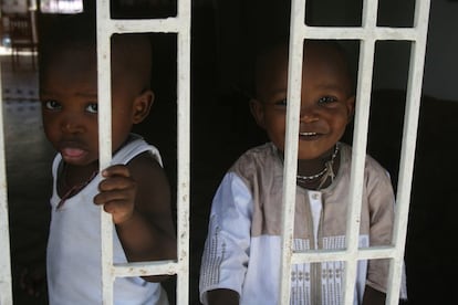 Mohamed y Moustapha se asoman a la ventana enrejada del salón de su casa, en el barrio de Liberté 1 (Dakar).