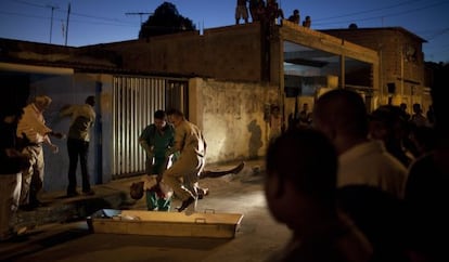 Workers place the body of a victim of Brazil's crime spree in a coffin