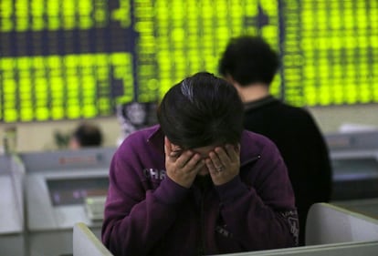 China sigue tomando medidas para evita el desplome de sus bolsas. En la foto, una mujer oculta su cara entre las manos mientras observa las cotizaciones en la pantalla de un ordenador en Nantong, al este de China, en la provincia de Jiangsu. 