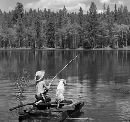 Un chico, ataviado al estilo de Huckleberry Finn, pesca en un lago.