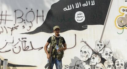 Un milicià de l'Exèrcit Sirià Lliure, davant un mural de l'ISIS a Yarablus.