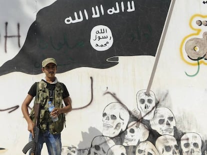 Un milicià de l'Exèrcit Sirià Lliure, davant un mural de l'ISIS a Yarablus.