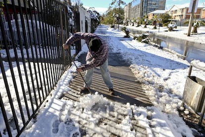 Un hombre limpia la nieve y el hielo de una acera a las puertas de una casa en Santiago, Chile, el 15 de julio de 2017.