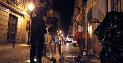 Un policía multa a dos jóvenes en julio pasado por hacer botellón.