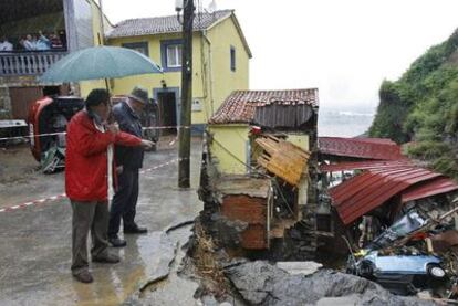 El alcalde del concejo de Gozón (Asturias), a la derecha, observa los destrozos provocados por la lluvia en Puerto Llampero.