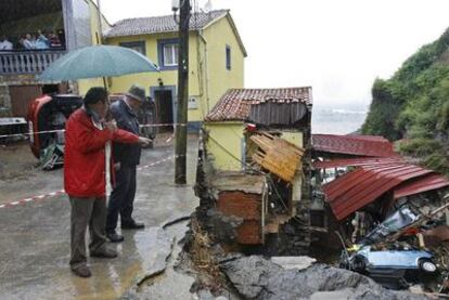 El alcalde del concejo de  Gozón (Asturias), a la derecha, observa los destrozos provocados por la lluvia en Puerto Llampero.