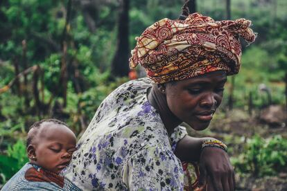 Una mujer con su bebé a cuestas en una plantación de yuca en Sierra Leona.