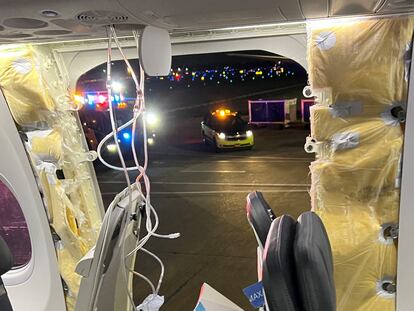 Passenger oxygen masks hang from the roof next to a missing window and a portion of a side wall of an Alaska Airlines Flight 1282.