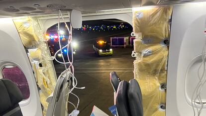 Passenger oxygen masks hang from the roof next to a missing window and a portion of a side wall of an Alaska Airlines Flight 1282.