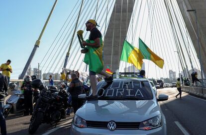 Homem vestindo uma bandeira do Brasil está em um carro com a frase "Fora Doria", enquanto apoiadores do presidente Jair Bolsonaro protestam contra as medidas de quarentena, em meio ao surto de doença por coronavírus, em São Paulo.