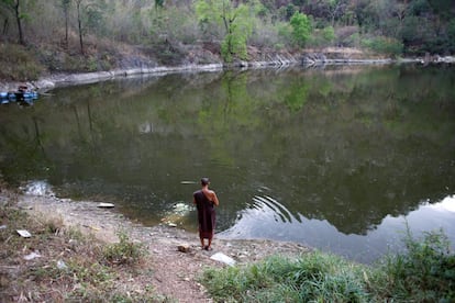 Un monje reza después de alimentar a peces y tortugas en un lago dentro del monasterio.