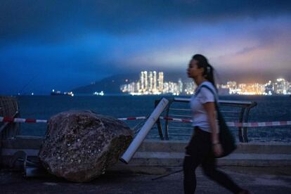 Una mujer pasa junto a una roca en la valla del paseo marítimo durante el tifón Mangkhut, en el distrito Tseung Kwan O (Hong Kong).