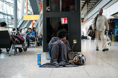 Una mujer se cubre con una manta mientras espera noticias sobre los vuelos cancelados de la compañía British Airways.