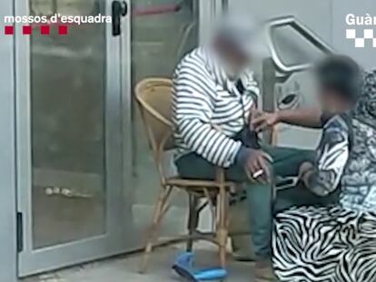 Una mujer registra a un hombre al que presuntamente obligaba a pedir limosna en la calle en Barcelona.