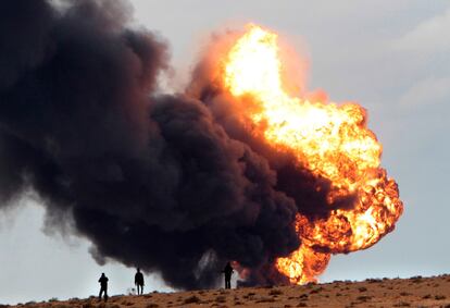 Un grupo de rebeldes observa la explosión causada por el bombardeo de las tropas de Gadafi contra un depósito cerca de Sedra.