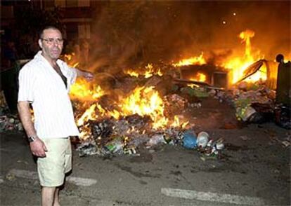 Un vecino de Málaga señala los contenderos incendiados en protesta por la huelga de limpieza.