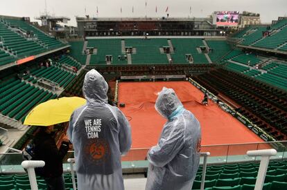 Tres espectadores con impermeables en la pista central.