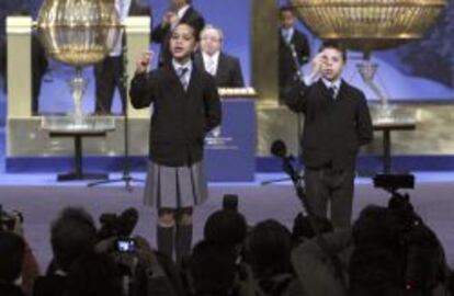 Los niños de San Ildefonso que han cantado el segundo premio muestran las bolas al público.