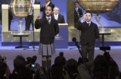 Los ni&ntilde;os de San Ildefonso que han cantado el segundo premio muestran las bolas al p&uacute;blico.