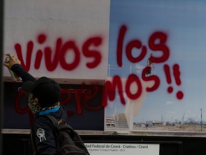Un manifestante en el octavo aniversario de la desaparición de los normalistas pinta por encima de una fotografía, el 26 de septiembre de 2022 en Ciudad de México.