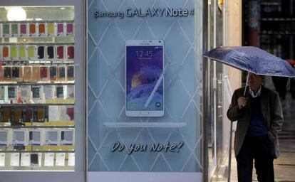 Un hombre junto a una tienda con un anuncio del Samsung Galaxy.
