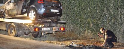 A police officer examines the scene where the burned vehicle of a murdered lawyer was found in Granada.