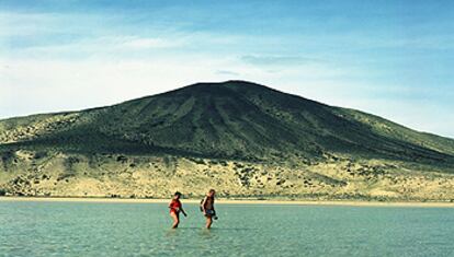 Una pareja cruza una laguna natural que la marea suele formar en la playa de sotavento de la península de Jandía, en Fuerteventura.