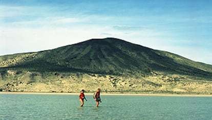 Una pareja cruza una laguna natural que la marea suele formar en la playa de sotavento de la península de Jandía, en Fuerteventura.