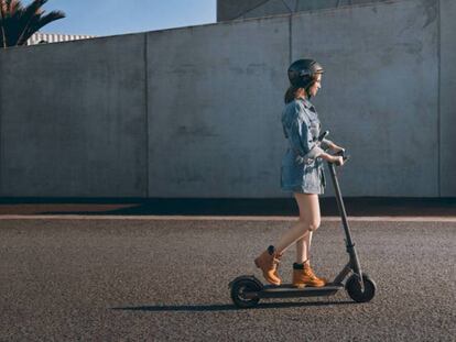 Una mujer pasea por la calle subida en el patinete eléctrico Xiaomi Mi Electric Scooter Pro.