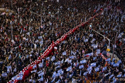 A line of protesters supporting women's rights, dressed as characters from The Handmaid's Tale television series, and other Israelis protest against plans by Prime Minister Benjamin Netanyahu's government to overhaul the judicial system in Tel Aviv, Israel, Saturday, March 25, 2023