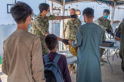 Soldados estadounidenses asisten a los evacuados afganos a su llegada a la base de Rota. / US NAVY