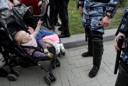 Policías antidisturbios montan guardia junto a unos niños durante la marcha anticorrupción en el centro de Moscú.
