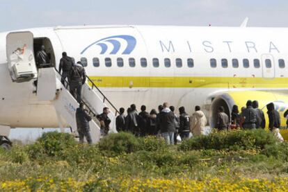 Un grupo de norteafricanos sube a un avión en Lampedusa rumbo a un centro de inmigrantes.