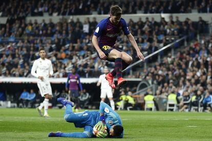 El portero madridista, Keylor Navas, atrapa un balón mientras el jugador del Barcelona, Sergi Roberto, le salta por encima.