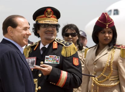 Berlusconi recibe a Gaddafi, acompañado por una de sus guardias personales, a su llegada al aeropuerto de Roma.