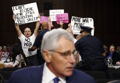 Manifestantes contra la guerra sostienen pancartas tras el Secretario de Defensa de EE.UU. Chuck Hagel que toma asiento para testificar en el Senado sobre la política de Estados Unidos hacia Irak y Siria en el Capitolio en Washington.