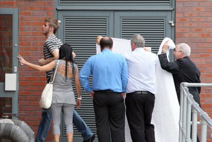 David de Gea entra en unas instalaciones de Manchester mientras unas personas intentan ocultar su presencia con sábanas.