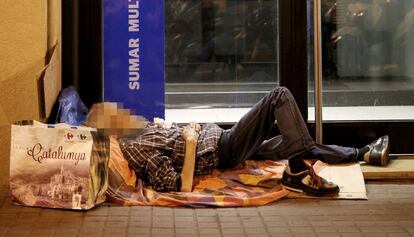 Un sin techo, durmiendo a la intemperie a las puertas de una oficina bancaria en Barcelona.