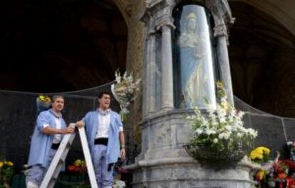 Dos 'blusas' se preparan para colocar los ramos de flores en honor a la Virgen Blanca.