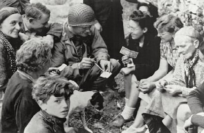 Joseph Vaghi, en el centro, de la Marina estadounidense, entabla una conversación con residentes de Colleville-Sur-Mer, un día después de que las fuerzas aliadas tomaran las playas de Normandía durante el Día D. Unos 156.000 miembros de los Aliados desembarcaron en Francia el 6 de junio de 1944 y Colleville fue una de las primeras localidades liberadas.