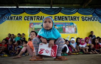 Una escolar de cinco años sostiene un cuaderno antes del inicio de las clases en una escuela improvisada para evacuados en Pantar, en la isla de Mindanao (Filipinas).