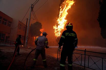 Las tareas de extinción continuaron durante toda la noche pero se vieron dificultadas por los fuertes vientos que alcanzaron fuerza siete en la escala de Beaufort. En la imagen, bomberos intentan apagar las llamas en el pueblo de Rafina (Grecia).