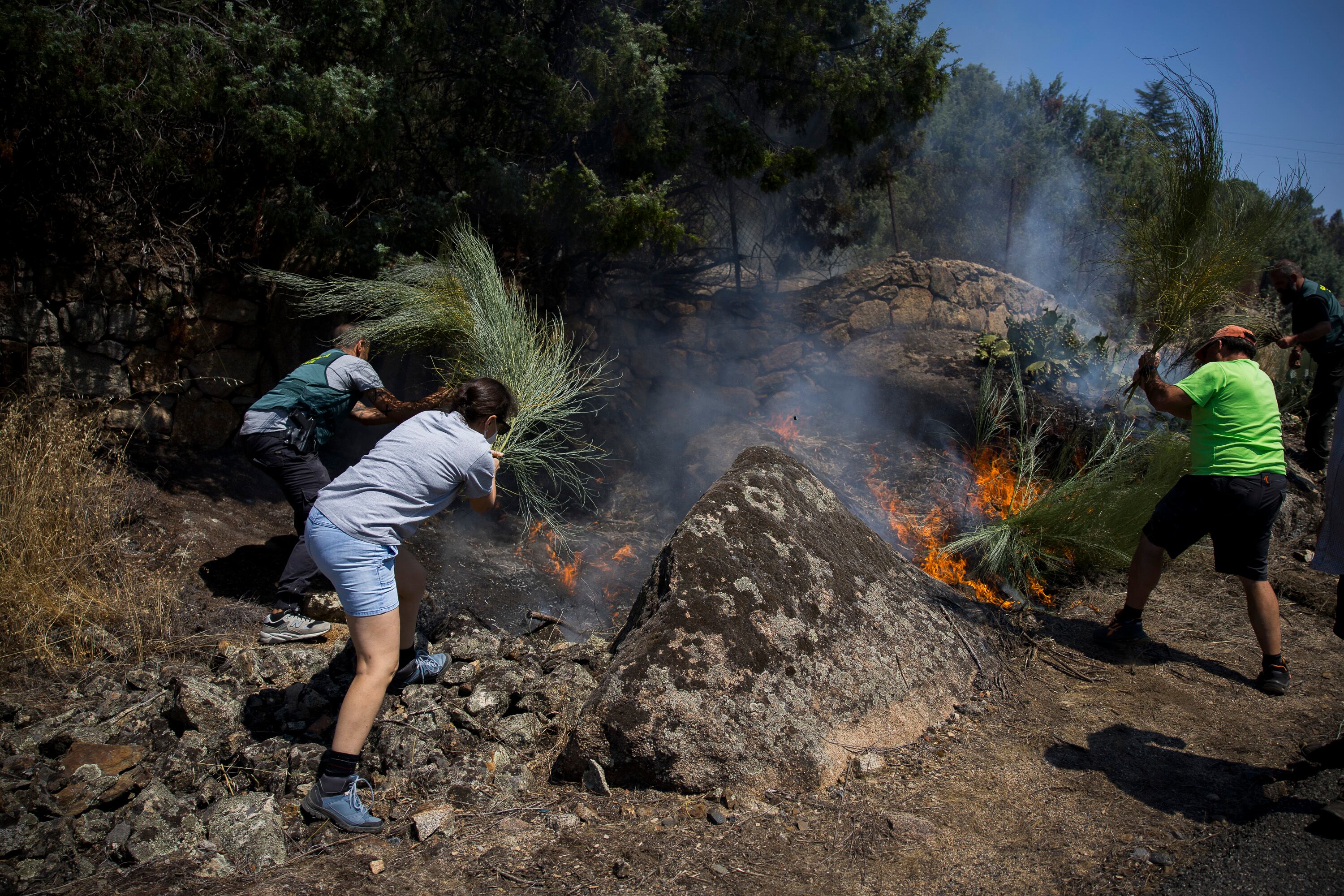 Vecinos y Guardia Civil luchan contra el fuego en un pequeño conato que se ha reactivado en la zona afectada por el fuego en Navaluenga.