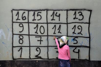 Una niña afgana cuenta en griego los números escritos en una pared durante una clase organizada por una ONG en un campo de refugiados de Atenas (Grecia). 