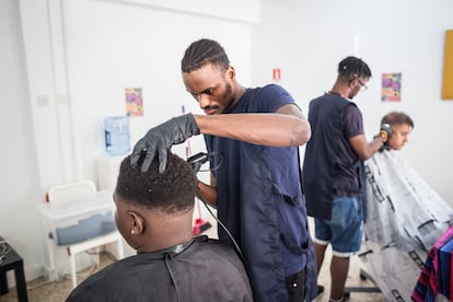 Un joven congoleño, solicitante de asilo, corta el pelo a una persona que ha acudido al Centro Dignidad de la ONG Refugee Support para utilizar este servicio gratuitamente, en Chipre, octubre de 2022.